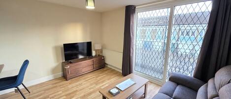 A modern living room with a flat-screen TV, a sofa, a coffee table, and a chair.