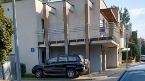 En byggnad med modern design, kännetecknad av ett platt tak och en balkong på översta våningen.