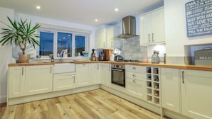 A modern kitchen with white cabinetry, a wooden countertop, and a large window. - Gordon Avenue (Camberley)