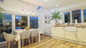 A modern kitchen with a dining table, chairs, and a potted plant. - Gordon Avenue (Camberley)