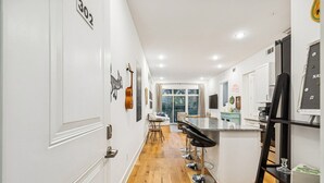 A modern kitchen with a central island, bar stools, and a dining area with a table and chairs. - Nashville Scene Suite in Chic East Nash, 12 min to Broadway! (Nashville)