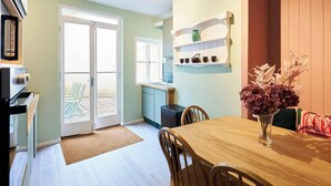 Een keuken met een eettafel, stoelen, een koelkast en een raam.
