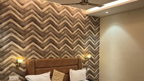 Een moderne slaapkamer met een wand in een herringbone-patroon, een houten hoofdbord en een plafondventilator.