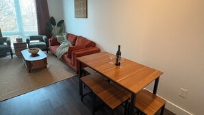 Een moderne woonkamer met een houten eettafel, een bank en een kleine bijzettafel.
