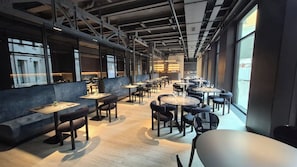 A modern restaurant with high ceilings, exposed beams, and large windows. Tables and seating are arranged in a spacious layout. - Palazzo Loreto Hotel Milano (Milan)