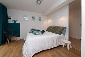 Un dormitorio con cama, una silla, un taburete pequeño y luces instaladas en la pared.