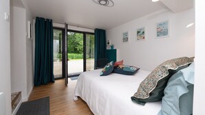 Een slaapkamer met een bed, een raam met gordijnen, een deur naar een buitenruimte en wanddecoratie.