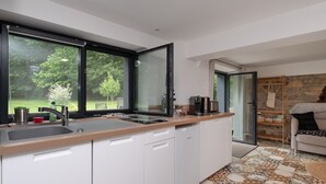 Een moderne keuken met een groot raam, een ingebouwde vaatwasser en een stenen muur op de achtergrond.