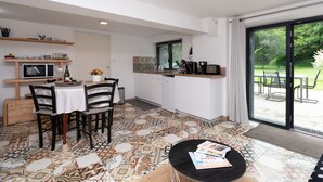 Een moderne keuken met een eetgedeelte, een groot raam en uitzicht op een tuin.
