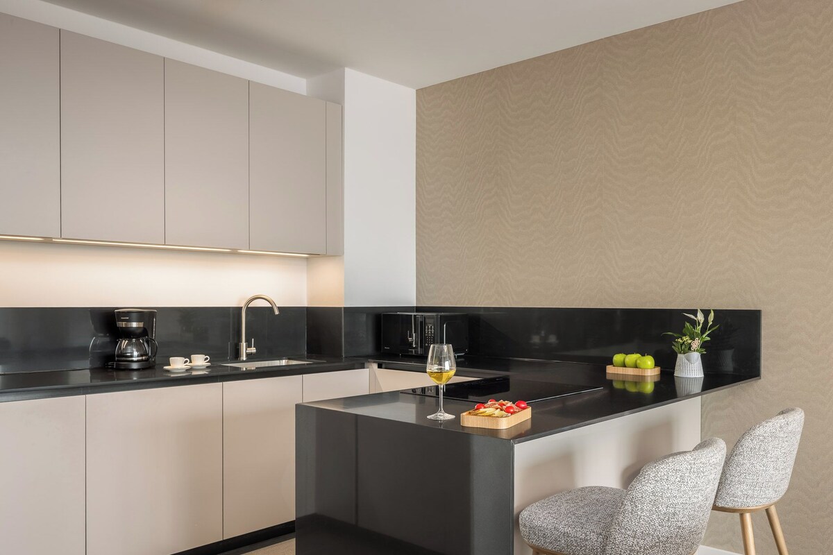 A modern kitchen with a central island, a coffee maker, and a wine glass.