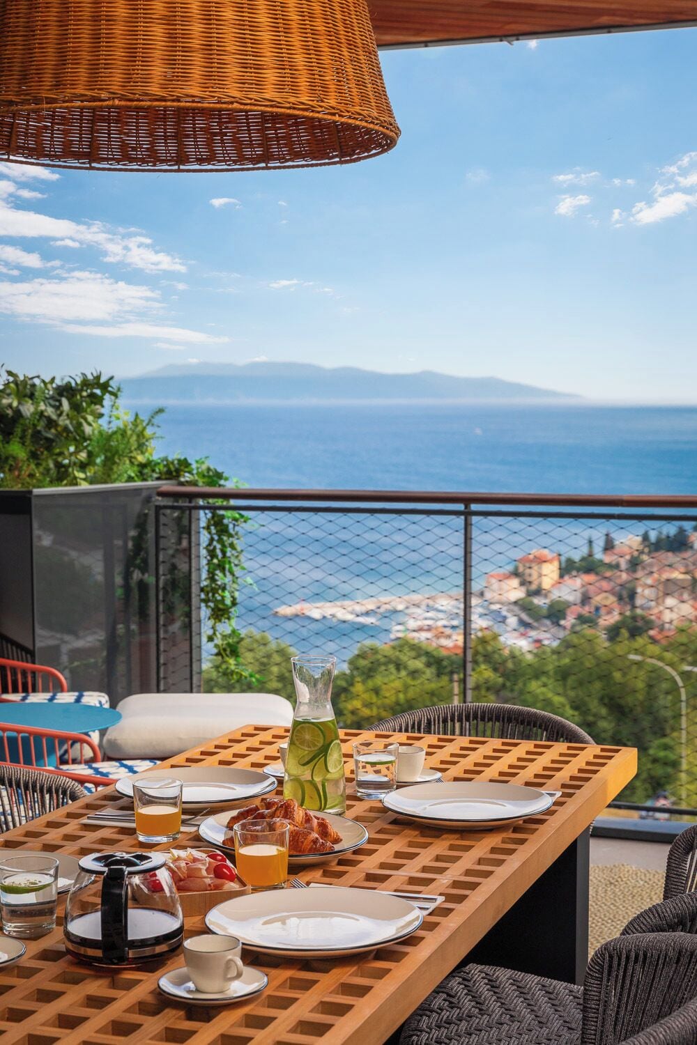 A table set for breakfast with a view of the sea and cityscape.