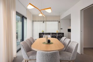 Un comedor moderno con una mesa redonda, seis sillas tapizadas e iluminación colgante.