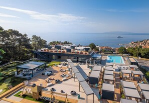 Una azotea moderna con piscina, asientos al aire libre y vistas al mar.