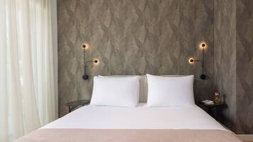 Una camera d'albergo con un letto, due comodini e illuminazione a parete.
