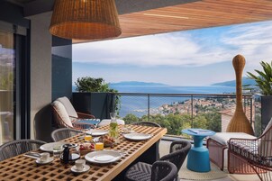 Un balcón con una mesa lista para el desayuno, con vistas a un pueblo costero.