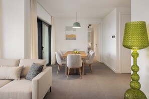 Una sala de estar moderna con un sofá, un comedor con una mesa y sillas, y una lámpara decorativa verde.