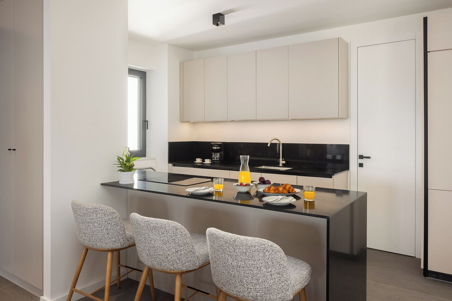 A modern kitchen with a central island, bar stools, and a breakfast setup.