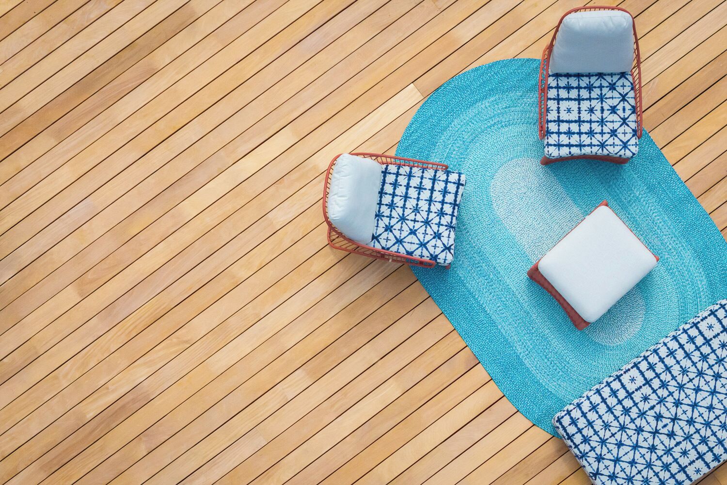 A wooden floor with two lounge chairs and a matching ottoman.