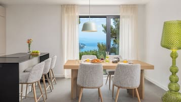 Un comedor con vistas al mar, una mesa dispuesta para el desayuno y una lámpara decorativa verde.