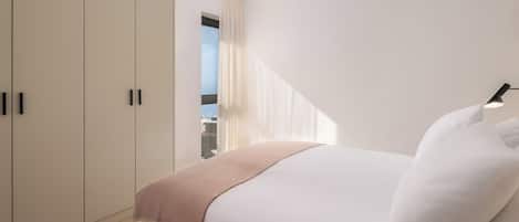 Een slaapkamer met een bed, een raam met gordijnen en een kledingkast.