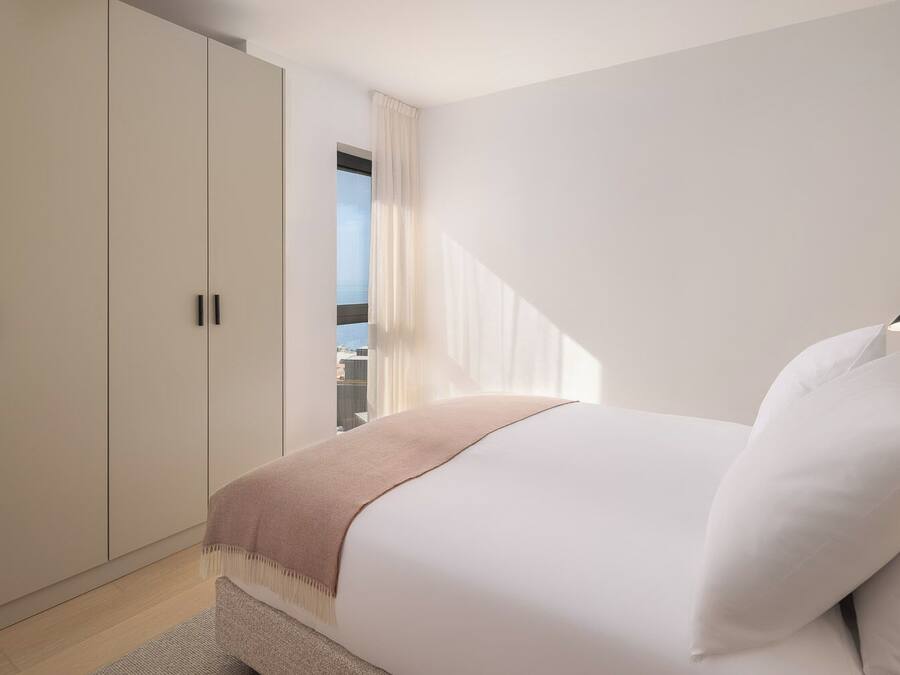 Quarto com cama, janela com cortinas e guarda-roupa.