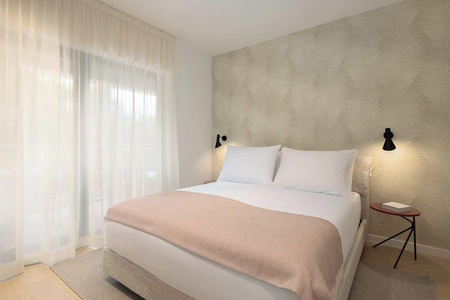 A modern hotel room with a large bed, a bedside table, and a nightstand.