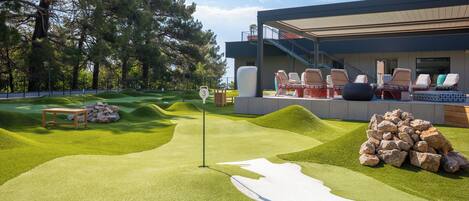 A modern building with a rooftop deck featuring outdoor seating and a putting green.