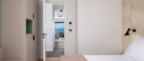 Une chambre à coucher avec un lit, une table de chevet, un bureau et une vue sur un balcon.