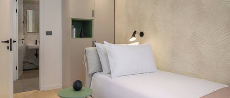 A bedroom with a bed, bedside table, lamp, wardrobe, and a mirror.