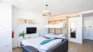 Et moderne hotelværelse med seng, fjernsyn, skrivebord og køjeseng.