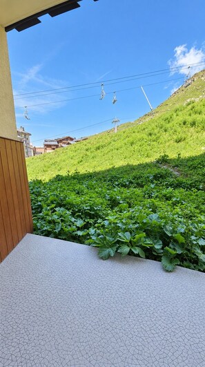 A terrace with a view of a green hillside and a clear sky. - Val Thorens - Ski In/Out - 4 Beds Flat (C-E19) (Les Belleville)