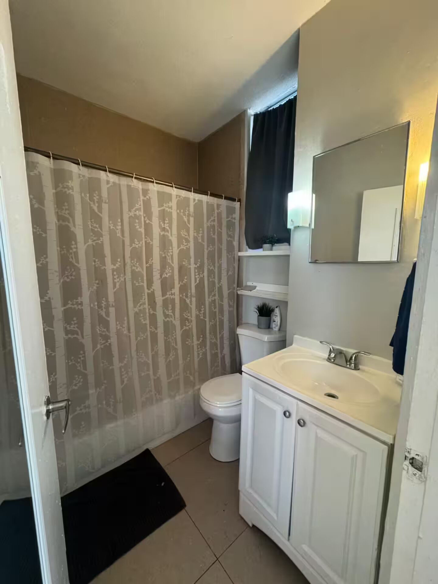 A bathroom with a toilet, sink, and shower curtain.