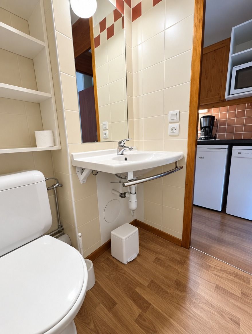 A bathroom with a toilet, sink, and white cabinets.
