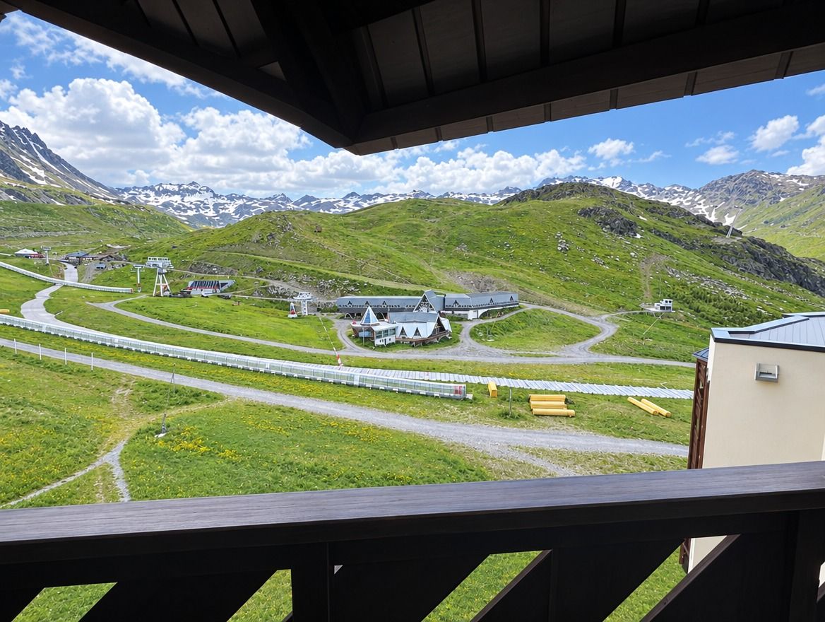 Een bergachtig landschap met een weg en gebouwen, waaronder een wit huis met een schuin dak.