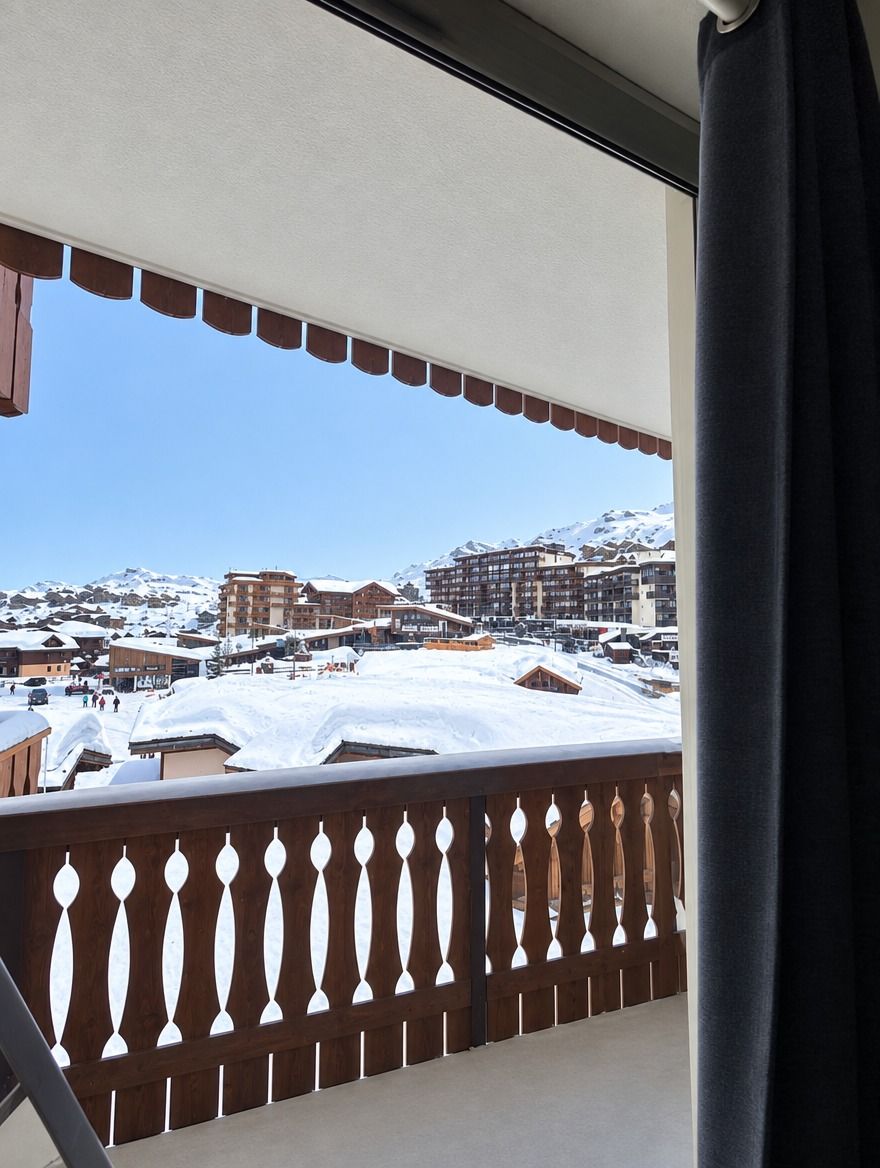 Un balcon avec vue sur une montagne enneigée et des bâtiments.