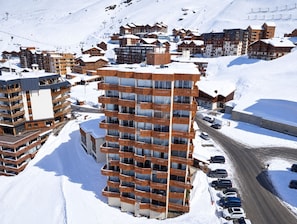 A multi-story hotel with balconies, situated in a snowy mountainous area with ski slopes in the background. - Val Thorens - Ski In/Out - 3 Beds Flat (D-315) (Les Belleville)