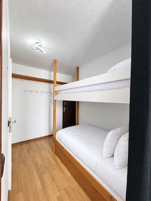 A bunk bed room with a wooden floor, a white ceiling light, and a door. - Val Thorens - Ski In/Out - 3 Beds Flat (D-315) (Les Belleville)
