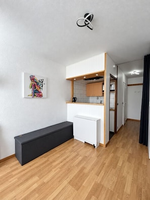 A modern kitchenette with white cabinets, a built-in microwave, and a bench. - Val Thorens - Ski In/Out - 3 Beds Flat (D-315) (Les Belleville)