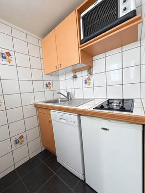 A compact kitchen with a dishwasher, a stove, and wooden cabinets. - Val Thorens - Ski In/Out - 3 Beds Flat (D-315) (Les Belleville)