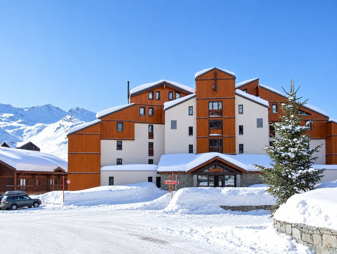 Un hôtel à plusieurs étages, doté d’une façade en bois, de toits enneigés et surplombant un paysage montagneux.