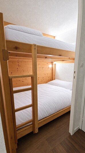 A bunk bed with a wooden frame and white bedding. - Val Thorens - Ski In/Out - 4 Beds Flat (J-C8) (Les Belleville)