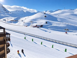 A snow-covered ski slope with a wooden building on the left and a red structure in the middle. - Val Thorens - Ski In/Out - 5 Beds Flat (M-603) (Les Belleville)