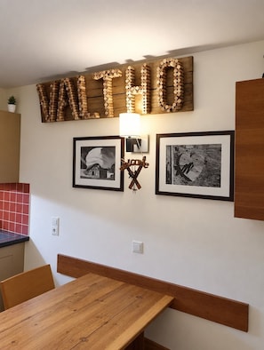 A wooden table with benches, a wall-mounted wooden sign spelling 'VALHOO,' and two framed black-and-white photographs. - Val Thorens - Ski In/Out - 5 Beds Flat (M-603) (Les Belleville)
