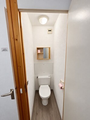 A small, narrow bathroom with a toilet, a wooden door, and a mirror on the wall. - Val Thorens - Ski In/Out - 5 Beds Flat (M-801) (Les Belleville)