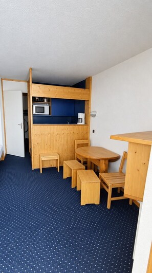 A compact room with a kitchenette, a dining table with chairs, and a small stool. - Val Thorens - Ski In/Out - 5 Beds Flat (M-803) (Les Belleville)