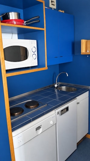 A compact kitchenette with a microwave, stove, sink, and white cabinets. - Val Thorens - Ski In/Out - 5 Beds Flat (M-803) (Les Belleville)