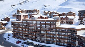 A multi-story hotel with a modern design, featuring balconies and large windows, situated in a snowy mountainous area. - Val Thorens - Ski In/Out - 6 Beds Flat (N-194) (Les Belleville)