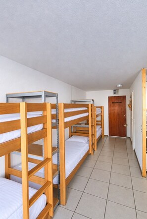A corridor with bunk beds aligned on one side, a wooden door at the end, and a tiled floor. - Val Thorens - Ski In/Out - 6 Beds Flat (N-194) (Les Belleville)