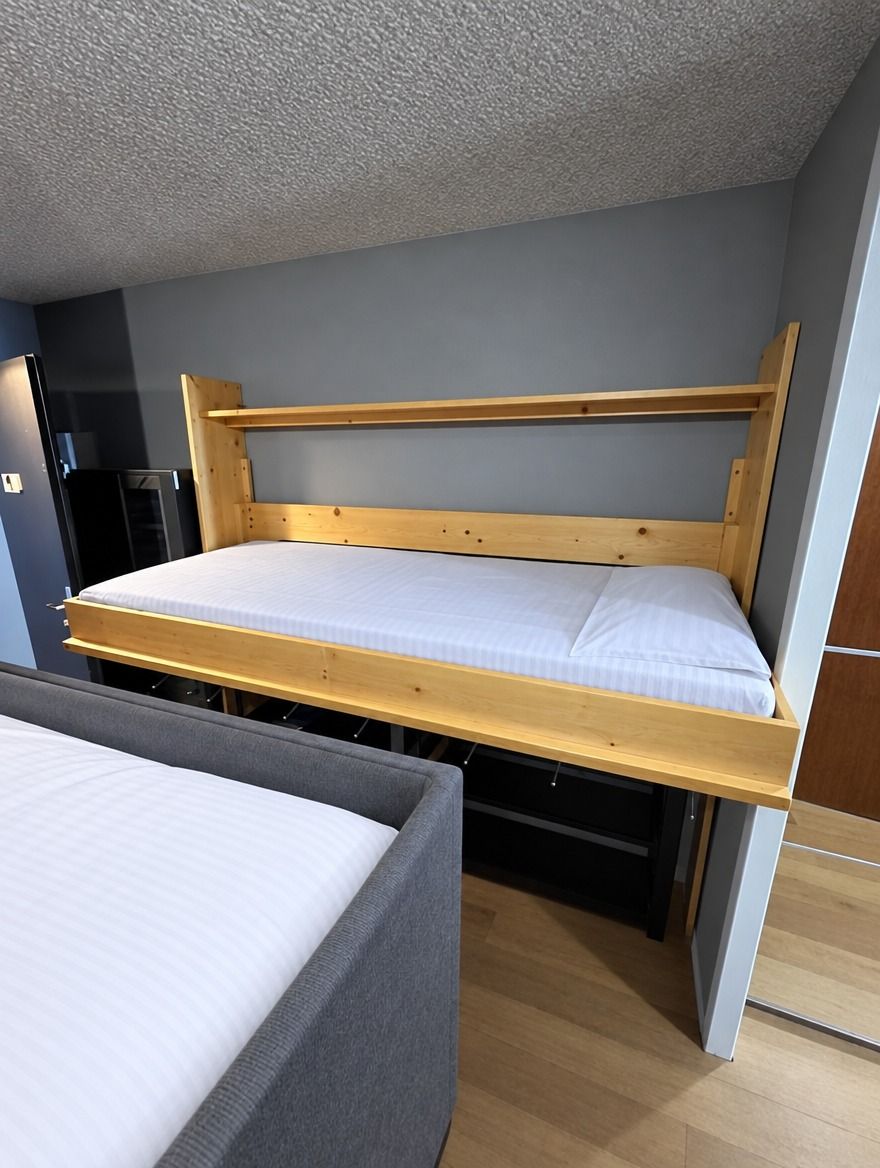 A bunk bed with a wooden frame and white bedding in a room with grey walls and a wooden floor.