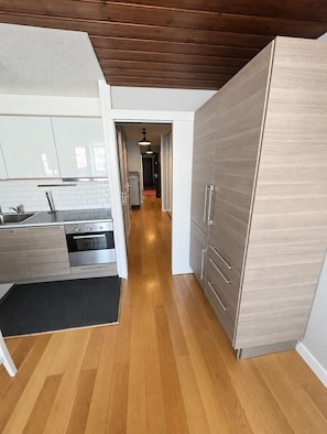 A modern kitchen with wooden flooring, a built-in oven, and a large cabinet. - Val Thorens - Ski In/Out - 7 Beds Flat (S-K10) (Val Thorens)